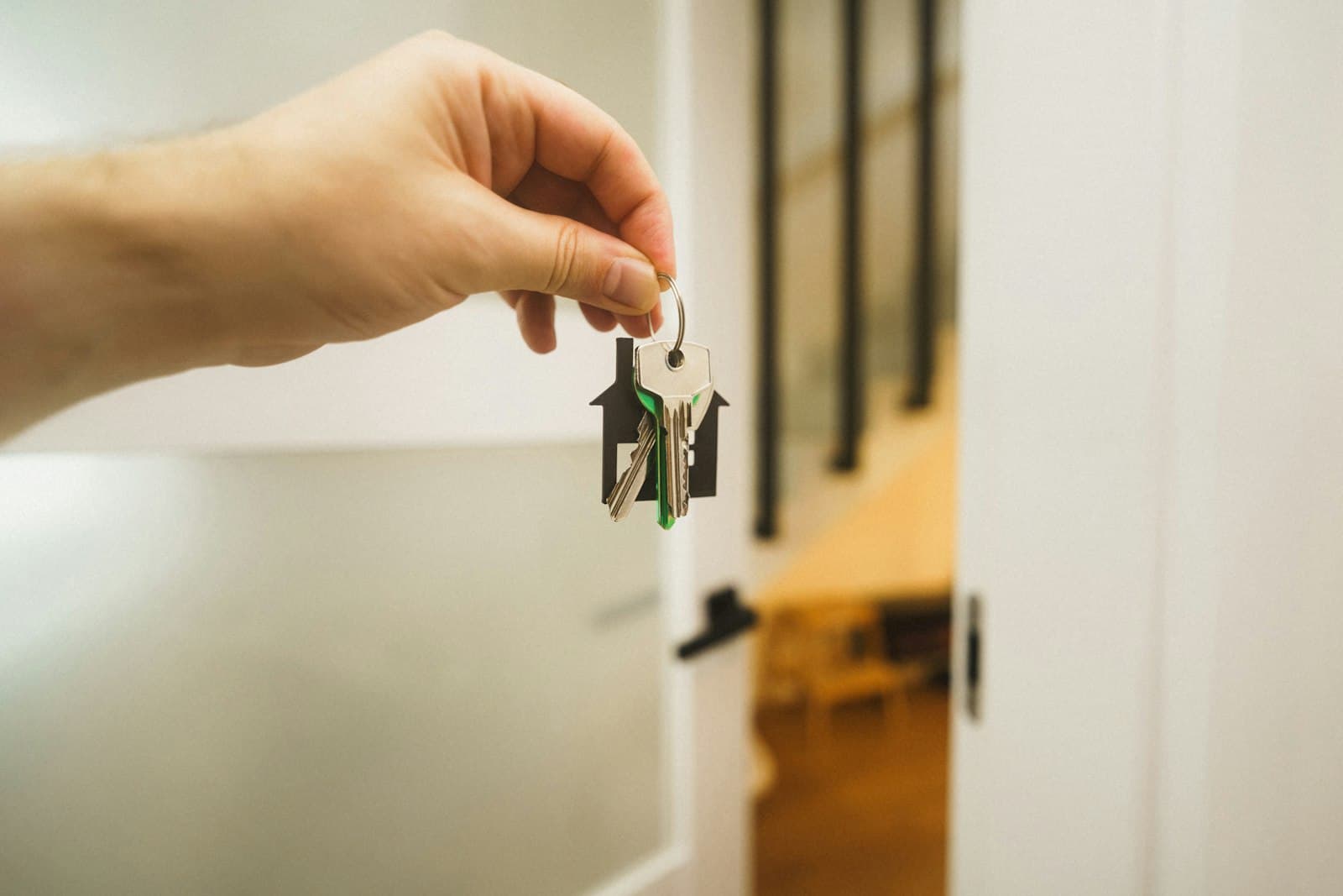 Hand holding house keys in front of an open door