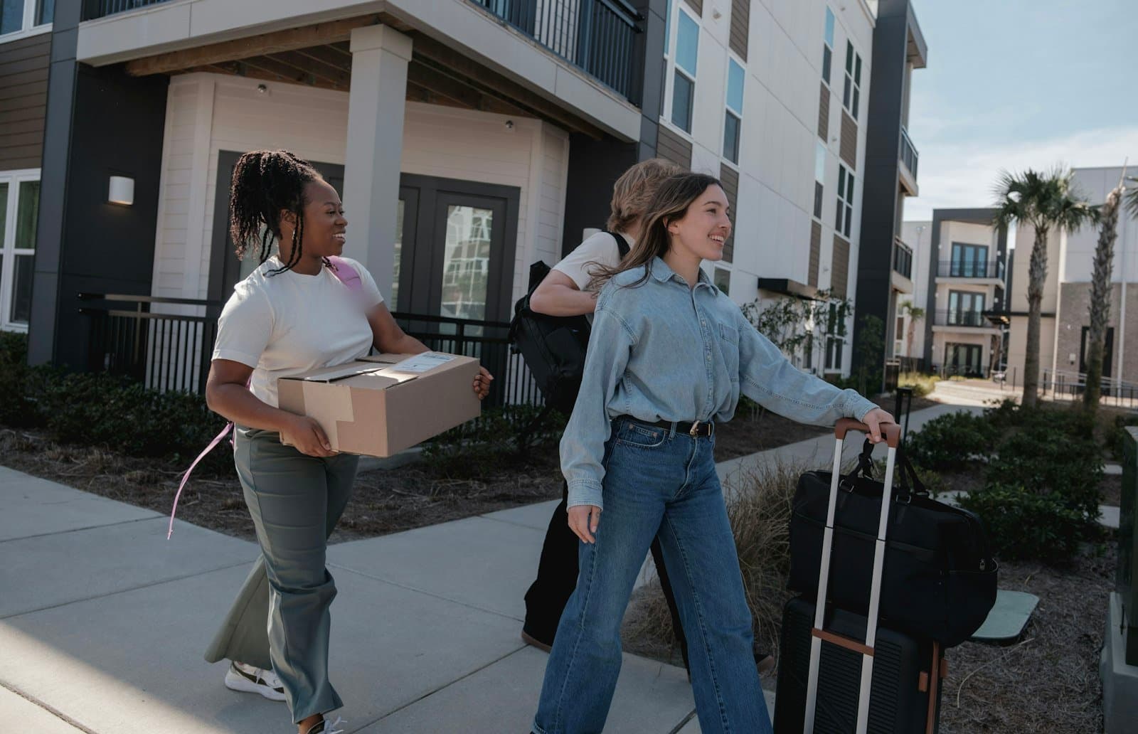 People carrying moving boxes outside an apartment building